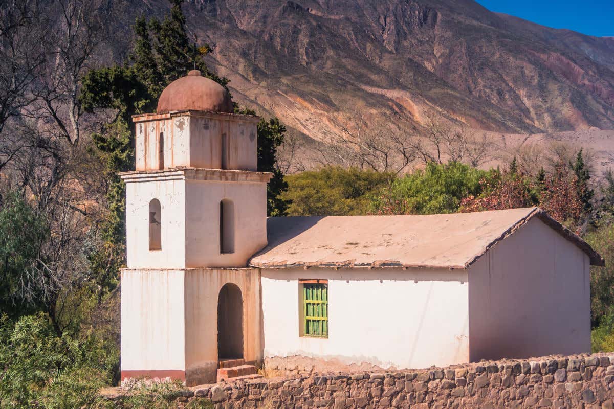 Una iglesia de aspecto antiguo y sencillo junto a un cerro en Argentina