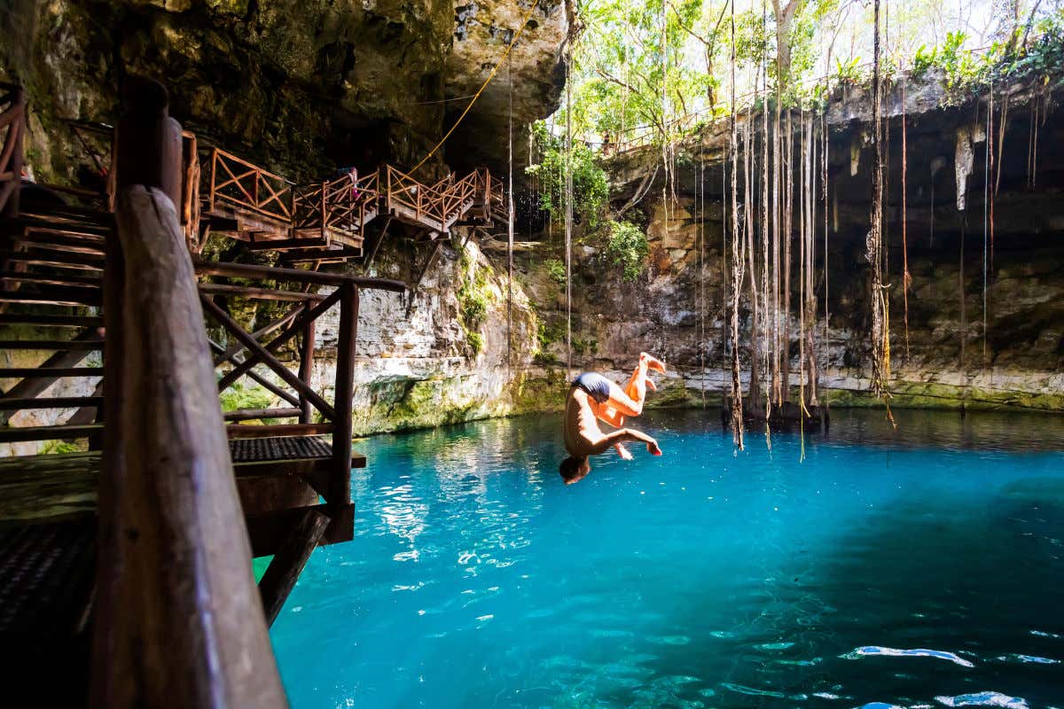 Un hombre lanzándose dando una voltereta hacia las aguas de un cenote en México