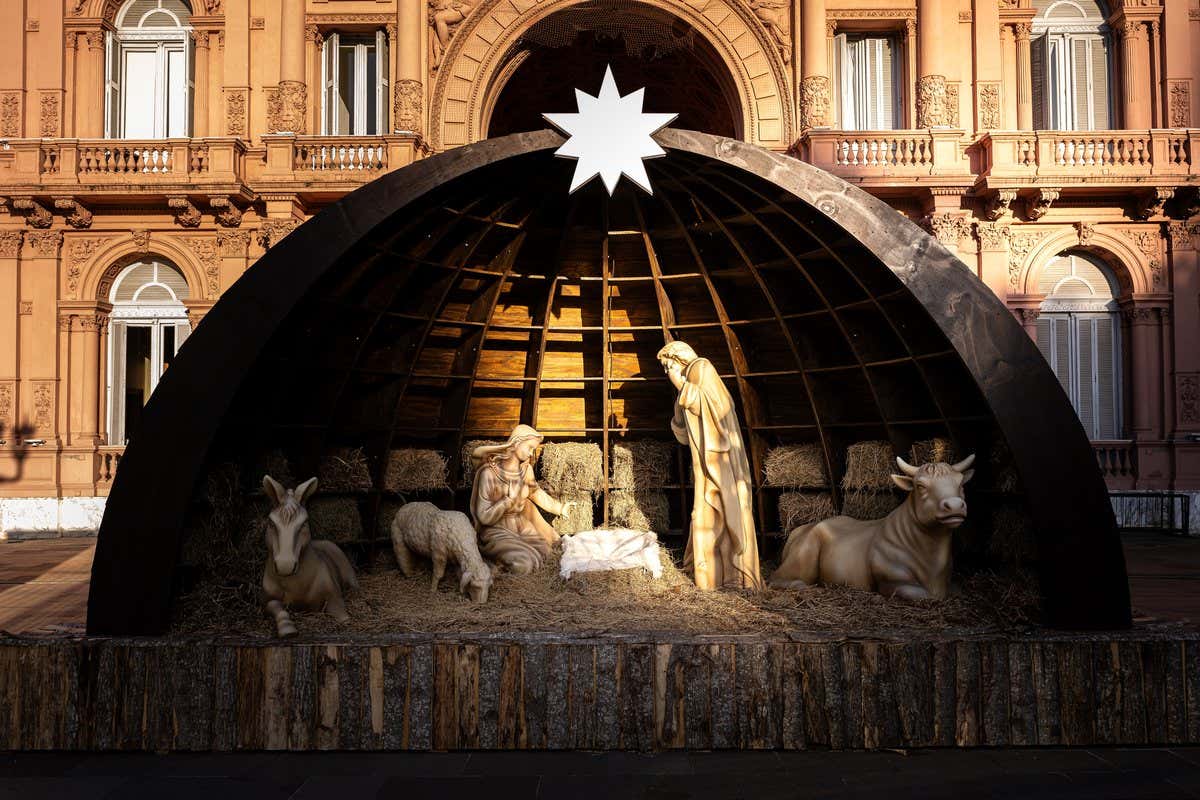 Pesebre navideño con figuras y estrella frente a un edificio histórico de fachada rosada en Buenos Aires