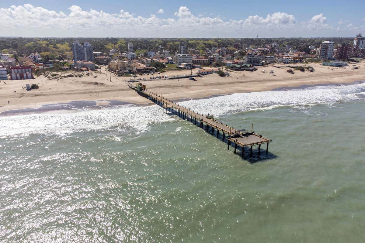 Aerial view of the beach at Villa Gesell surrounded by dunes with a wooden walkway running toward the sea