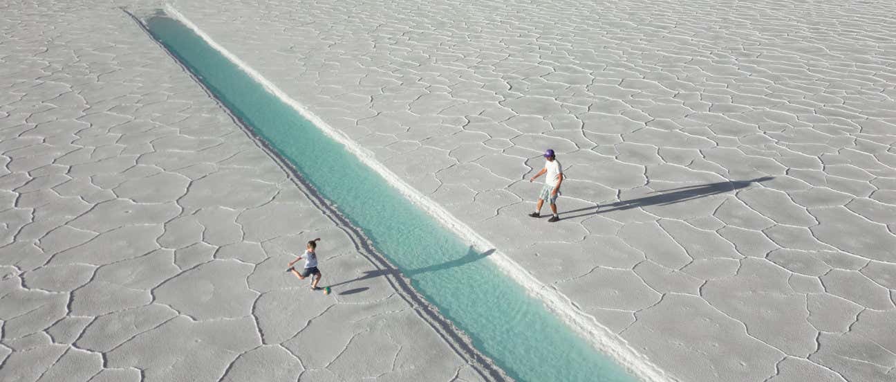 Un padre y un hijo jugando con un balón en mitad del paisaje blanco de las Salinas Grandes de Jujuy y Salta