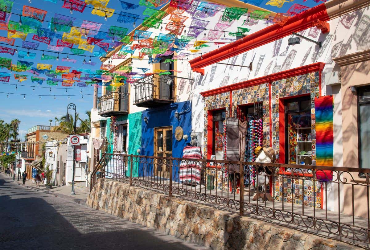 A colorful street in Los Cabos with ornate buildings and street decorations.