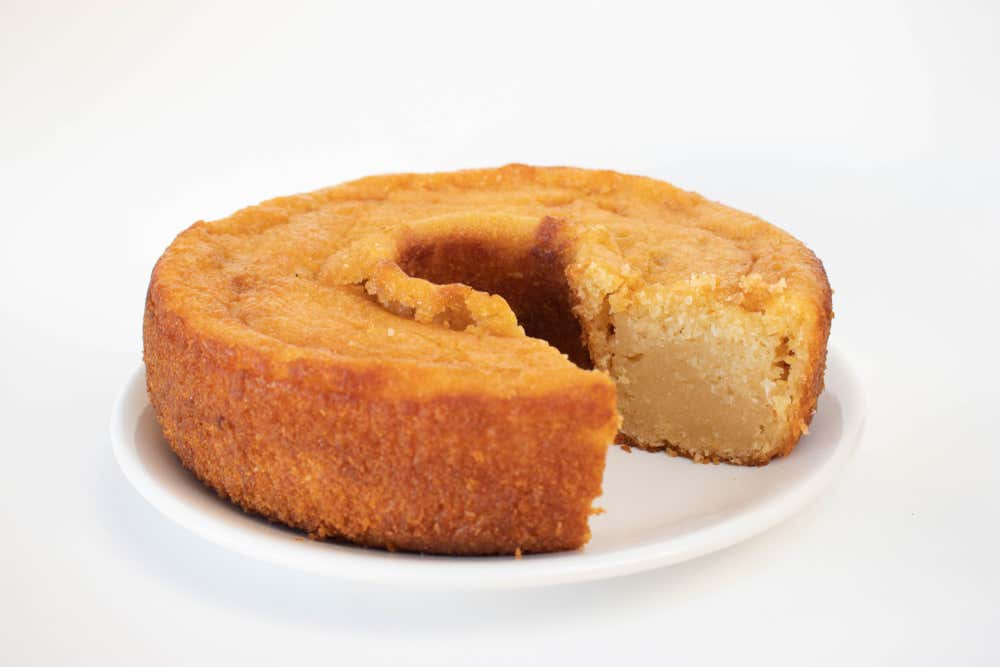 Detalhe de um bolo de macaxeira, preparado com mandioca ralada e leite de coco, servido em um prato branco