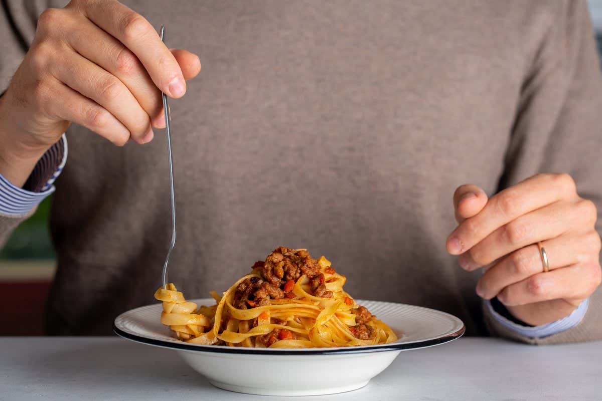 Persona a punto de comer un plato de tagliatelle con ragú de carne
