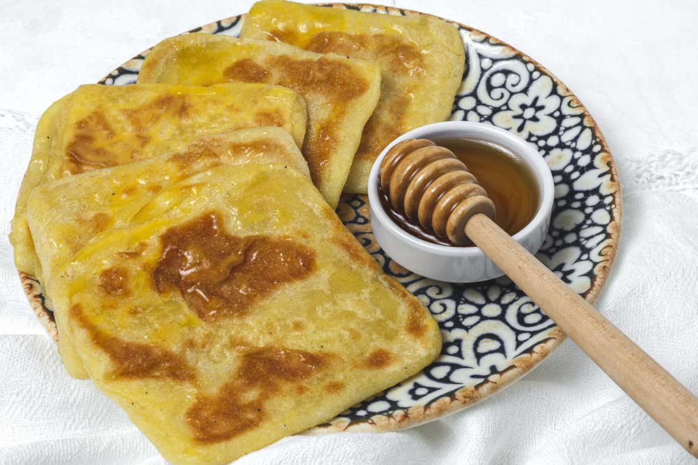 Detalhe de um rghaif ou msemen marroquinos, panquecas tradicionais servidas com mel e queijo cremoso, em um prato branco