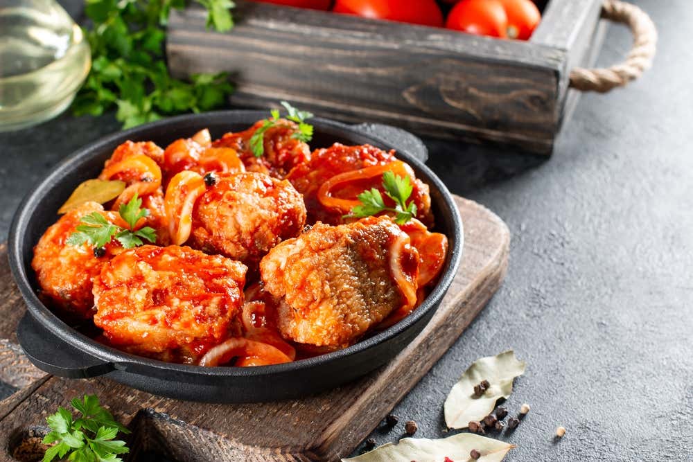 Moqueca baiana, um ensopado tradicional brasileiro de peixe com filé acompanhado de molho de tomate, servida em uma panela de ferro