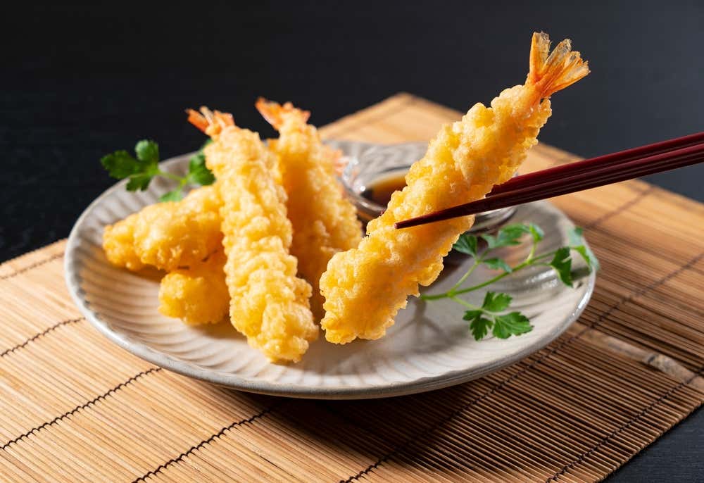 Tempura de camarão, um clássico da culinária japonesa, servido em um prato sobre fundo preto