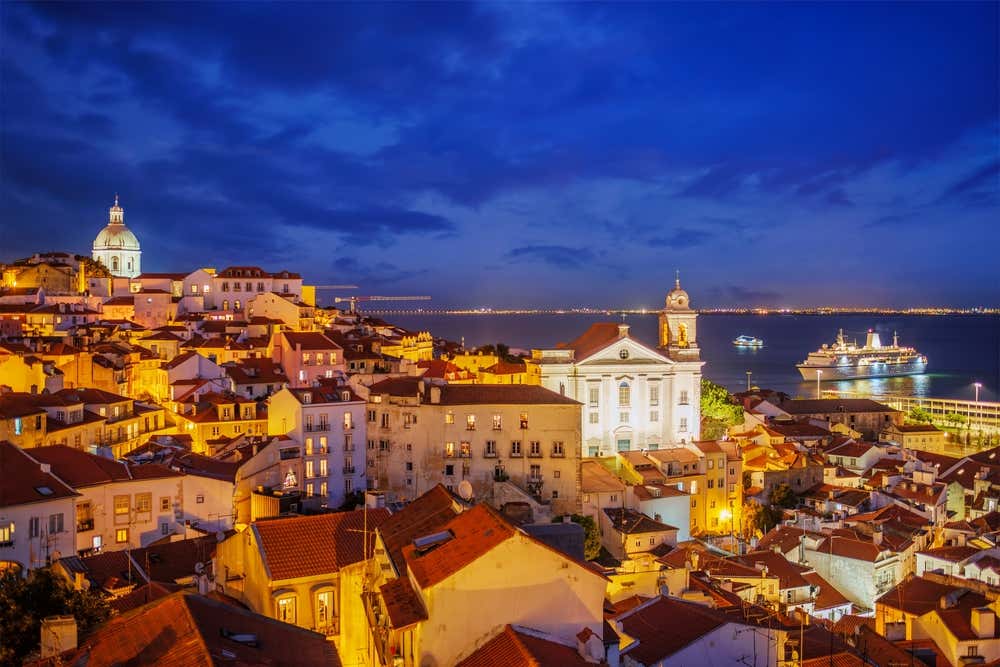 Vista de Lisboa do mirante turístico Miradouro de Santa Luzia, com vista para o centro histórico de Alfama à noite, durante um cruzeiro