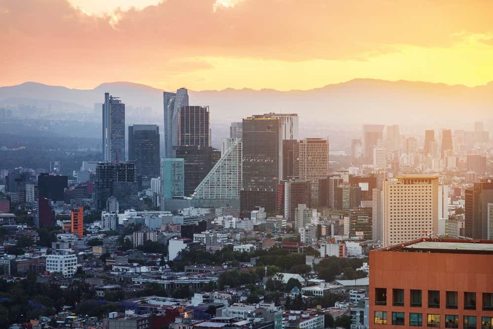 Vista aérea da Torre Latinoamericana, dos arranha-céus e das montanhas do centro da Cidade do México ao entardecer