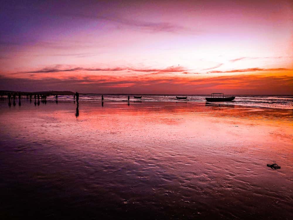 Entardecer em Jericoacoara, no Ceará, Brasil, com o céu em tons dourados e alaranjados iluminando a praia, as dunas e o mar em um cenário típico do litoral nordestino