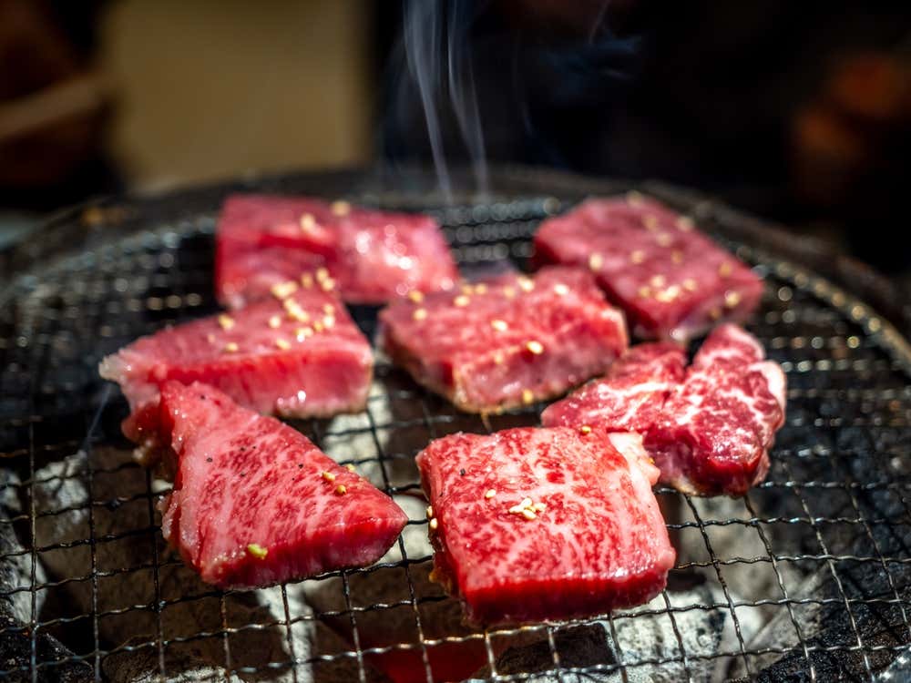Carne Wagyu japonesa A5 grelhada no estilo yakiniku, com marmoreio intenso e sabor marcante, chiando sobre a grelha quente