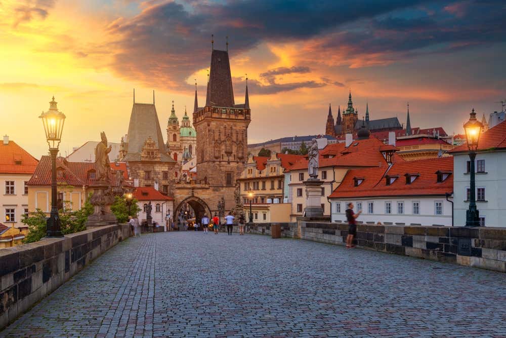 Vista panorâmica da Ponte de Carlos ao entardecer, cercada pelas construções históricas e pelo charme do centro de Praga, República Tcheca