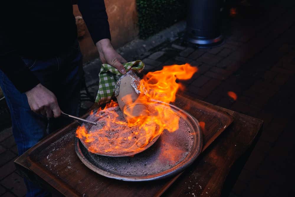 Chef preparando o tradicional testi kebab turco sobre fogo a lenha, em um restaurante de Istambul