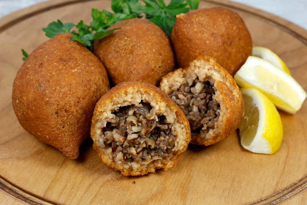 İçli köfte, prato tradicional da culinária turca, servido com limão sobre uma tábua de madeira