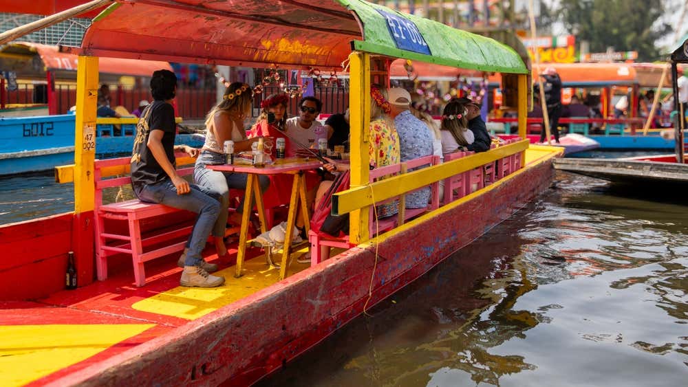 A group of people sitting on a boat floating in Xochimilco in Mexico City.