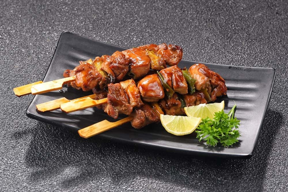 Yakitori, tradicional espeto japonês de frango grelhado, preparado com pequenos pedaços de carne servidos em palitos de bambu