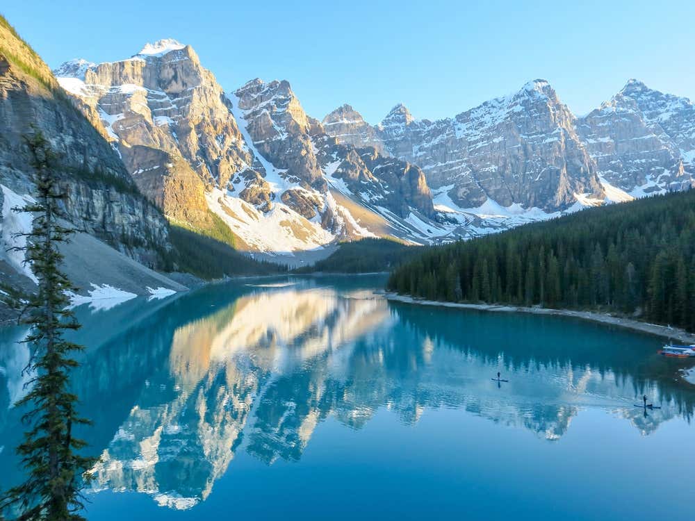 Moraine Lake, Alberta, with snowy mountains and a clear sky in the background.