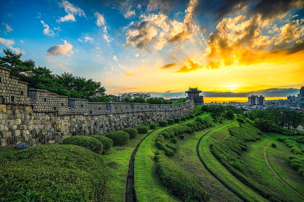 Vista da Fortaleza de Hwaseong ao pôr do sol, em Suwon, na Coreia do Sul, com suas muralhas históricas sob a luz dourada do entardecer