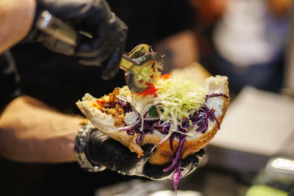 Chef adicionando tomates ao sanduíche de döner kebab