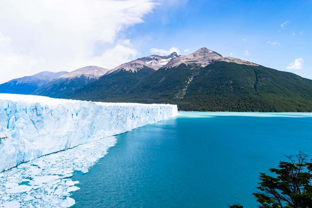Vista panorâmica da parede glacial do Perito Moreno, com blocos de gelo flutuando nas águas e montanhas ao redor, no Parque Nacional Los Glaciares, na Argentina