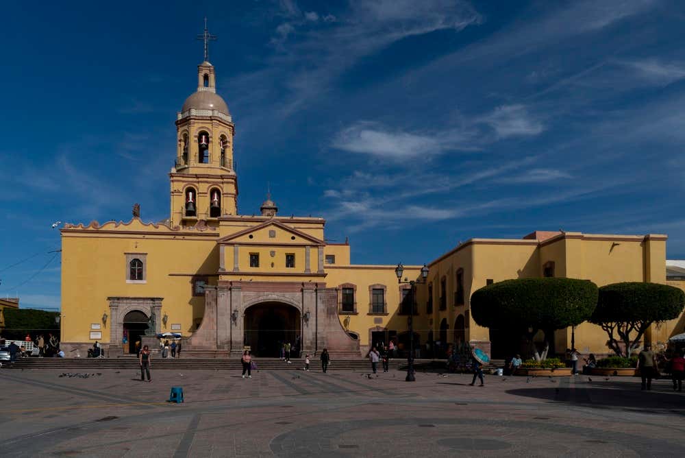 The Templo de la Santa Cruz in Querétaro on a quiet morning, with a few people standing outside of the main square.