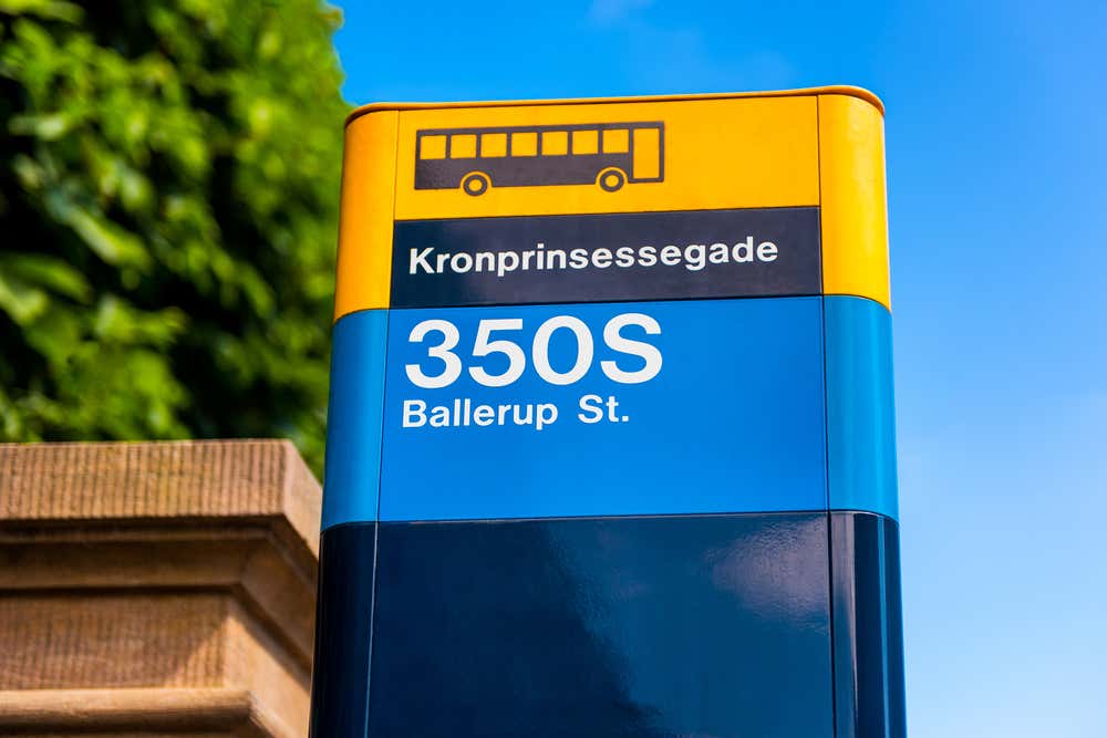 Primo piano di un cartello giallo, blu e nero della fermata dell'autobus a Copenaghen, con l'icona di un bus, il nome della fermata Kronprinsessegade e la linea 350S diretta a Ballerup St