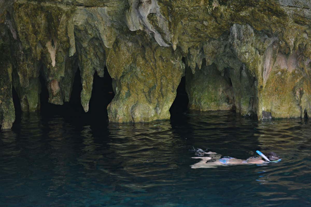 Una mujer haciendo snorkel en las aguas del Gran Cenote de Tulum