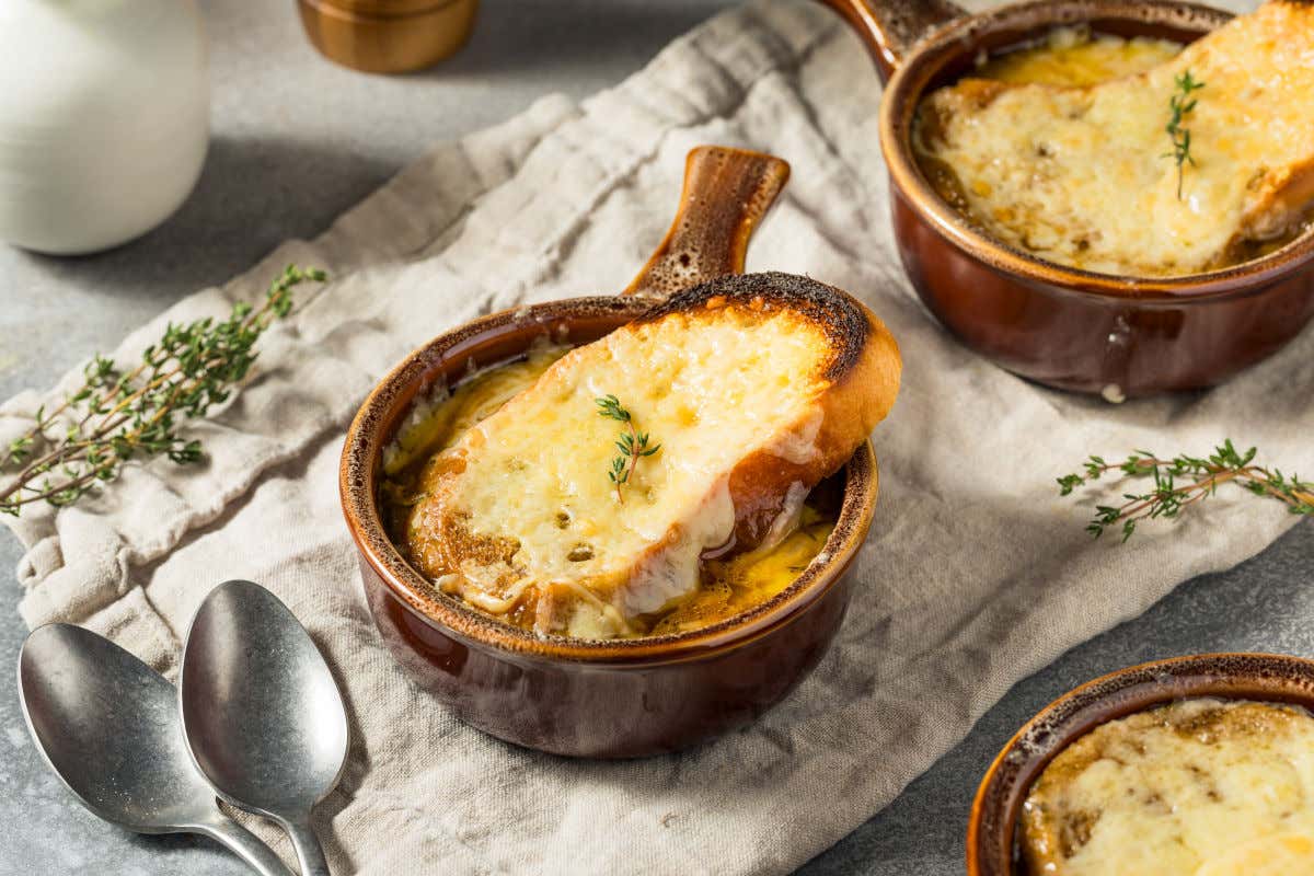 Pequeñas cazuelas de barro con sopa de cebolla y pan con queso gratinado