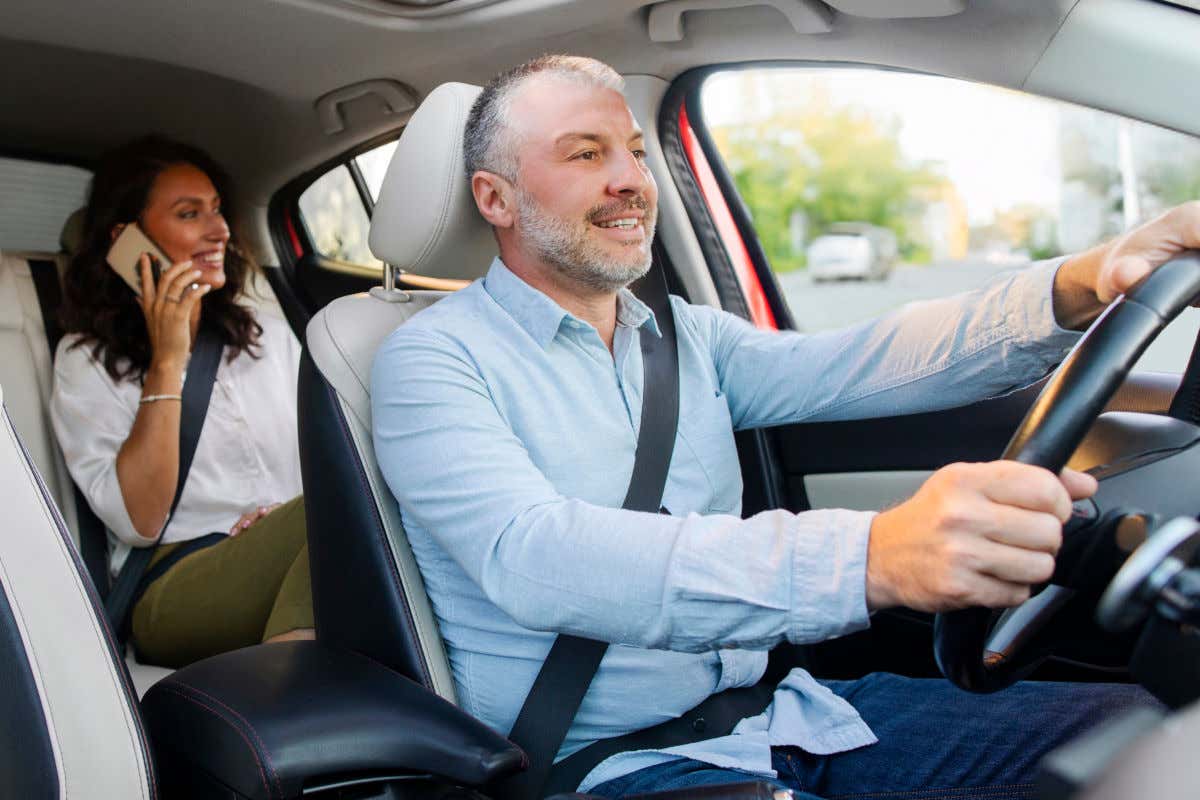 Un conductor de un coche llevando a una mujer que va de pasajera y está hablando por el móvil
