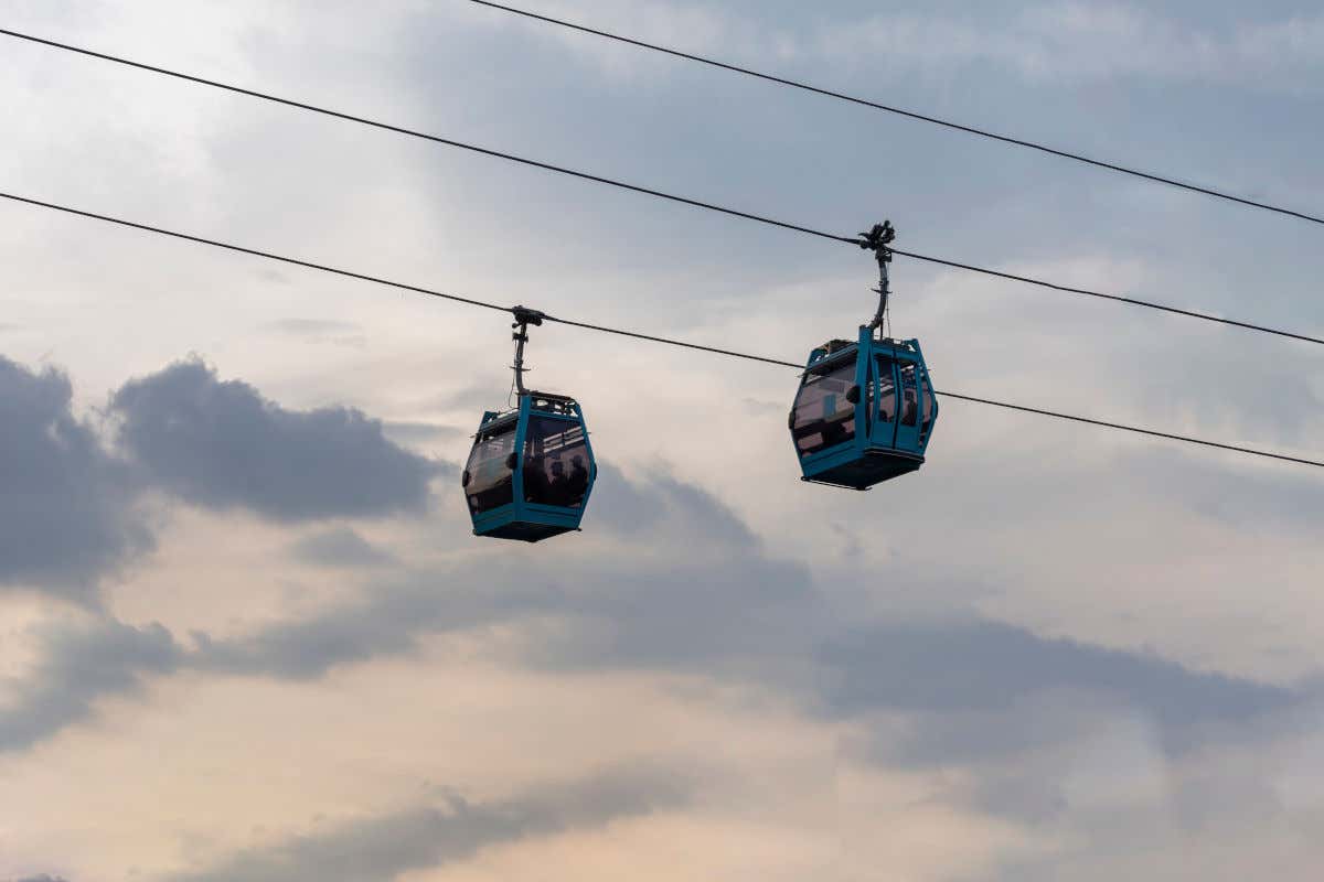 Dos cabinas del teleférico de Ciudad de México realizando un viaje en un día con algunas nubes