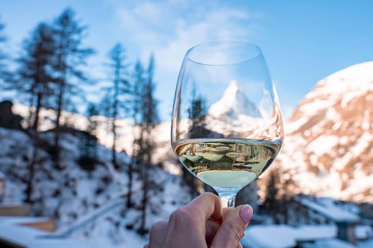 Una copa de vino blanco de Suiza frente a unas montañas nevadas