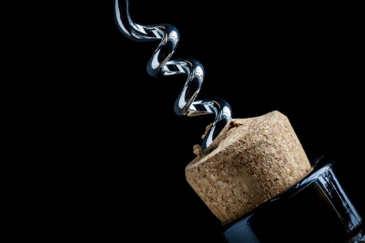Primer plano de un sacacorchos extrayendo el corcho de una botella de vino sobre fondo negro