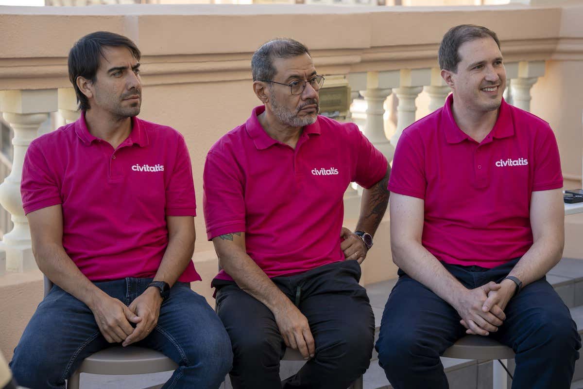 Nicolás Posse, Alexandre Oliveira y Juan Rossello con polo rosa de Civitatis sentados en una terraza