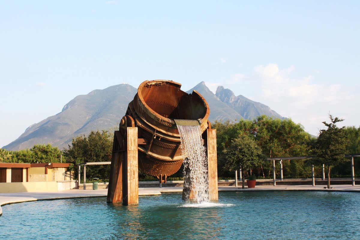 Escultura industrial reconvertida en fuente de agua en el Parque Fundidora, con el Cerro de la Silla al fondo