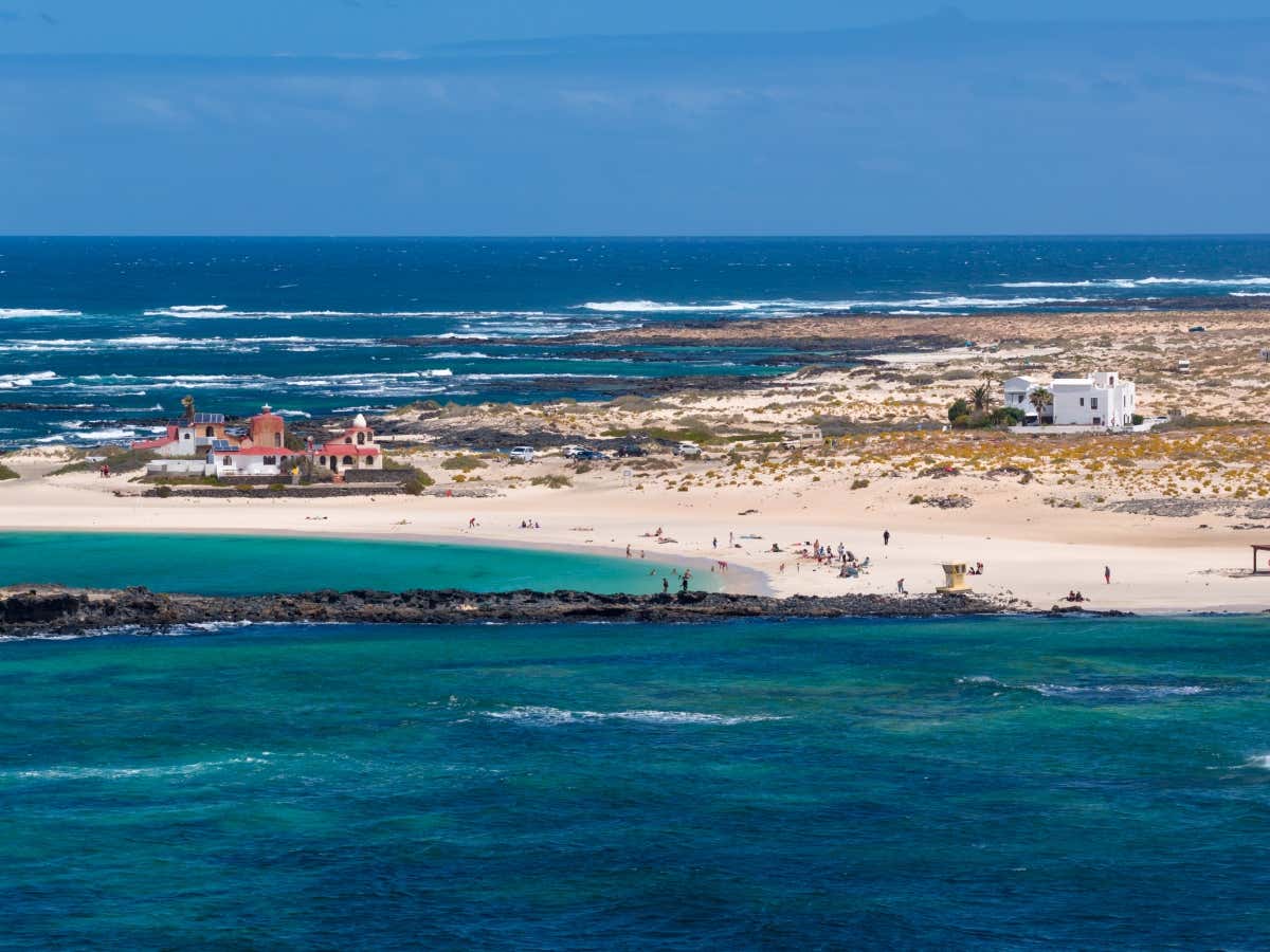 Varias personas bañándose en las aguas cristalinas y arena blanca en la playa de la Concha