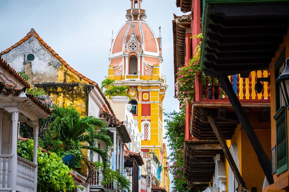 Rua colorida no centro histórico de Cartagena das Índias, na Colômbia, com fachadas vibrantes e elementos que refletem a diversidade cultural da cidade caribenha