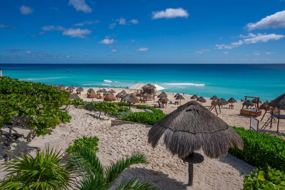A shot of Playa Delfines seen from above with various parasoles and the blue sea in the background.