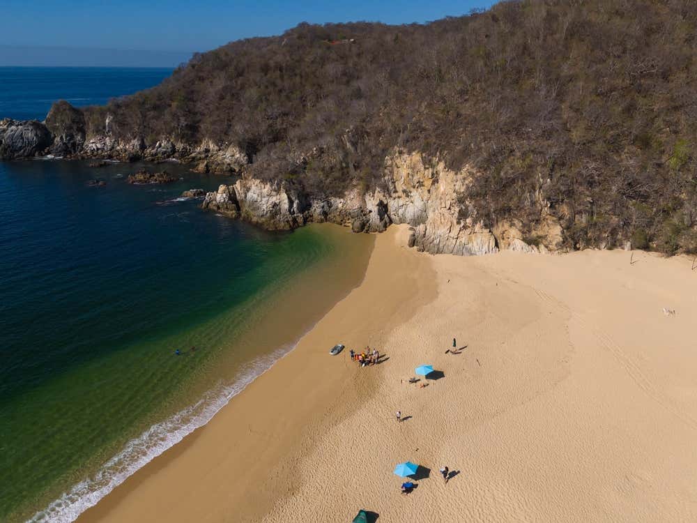 Playa Cacaluta vista desde arriba con una sombrilla y algunas personas relajándose al sol