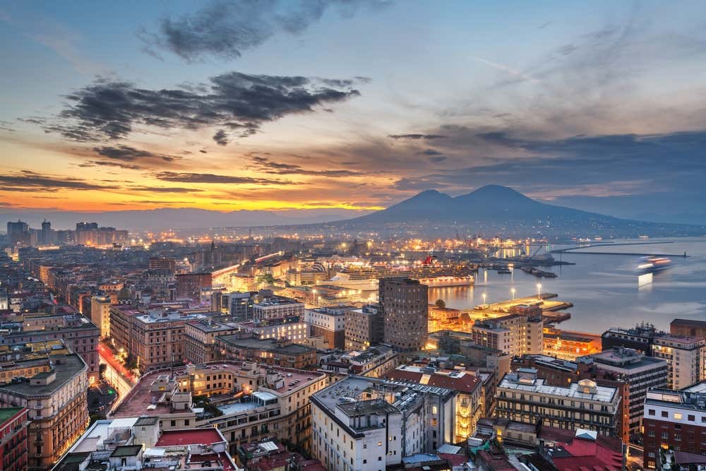Perfil de Nápoles al amanecer, con la ciudad y el puerto en primer plano y el monte Vesubio al fondo