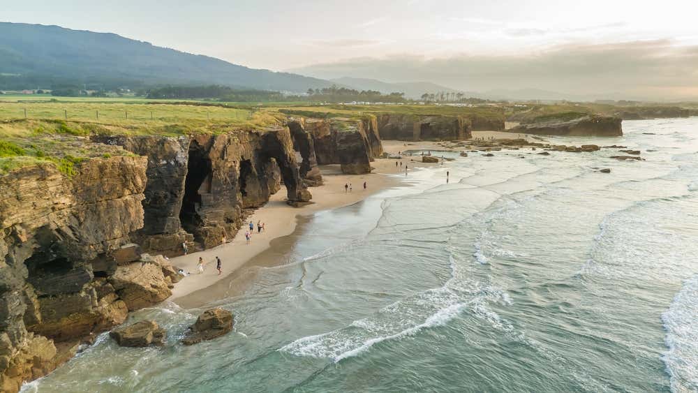 Vista aérea da Praia das Catedrais ao entardecer, na Galícia, norte da Espanha, famosa por suas impressionantes formações rochosas na costa cantábrica