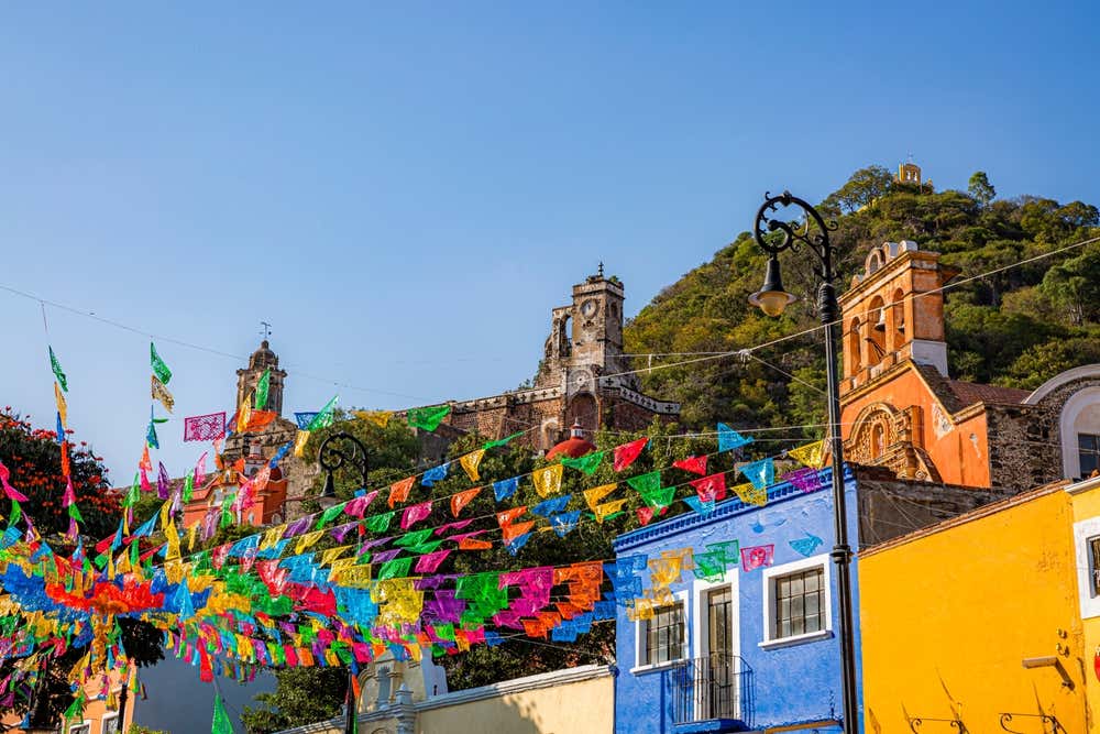 Colorful houses in Atlixco with bright garlands and a clear sky in view.