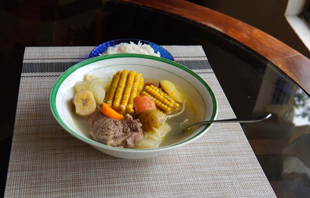 Olla de carne served with corn on the cob, meat, carrot and more.