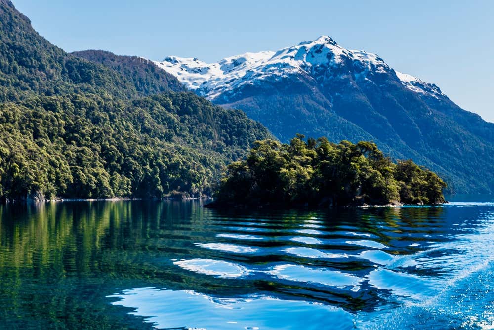 Embarcação navegando pelo lago Nahuel Huapi, em Puerto Blest, com as paisagens montanhosas da região de Bariloche ao redor