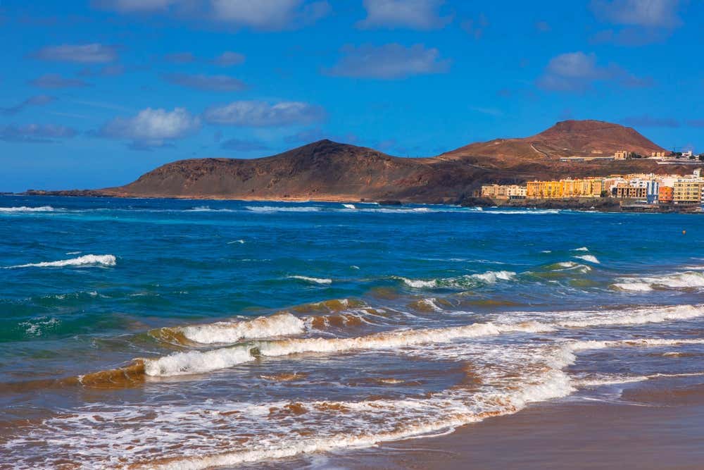 Praia de Las Canteras, em Las Palmas de Gran Canaria, Espanha, com areias douradas, águas azuis e a paisagem urbana da cidade ao fundo