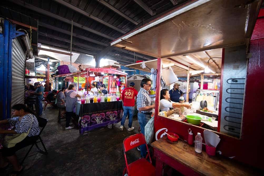 Lucas de Gálvez market with various food and drink stands with people queuing up and eating food.