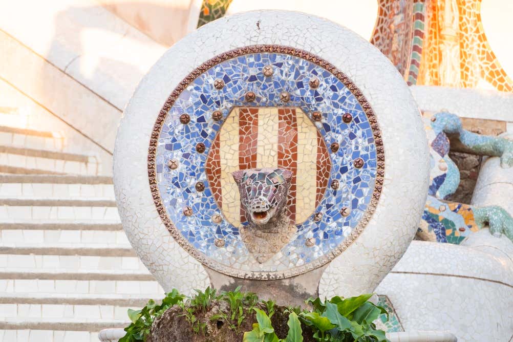 Dettaglio del medaglione in ceramica con la testa di drago e la bandiera della Catalogna, situato sulla scalinata monumentale di Parc Güell a Barcellona