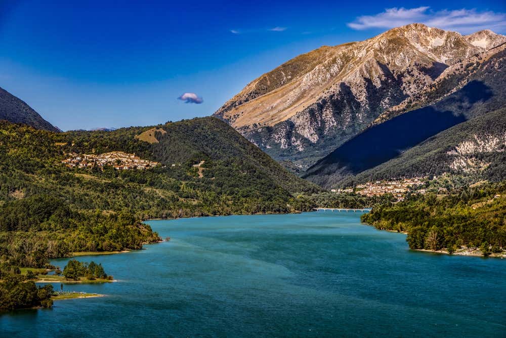 Vista panoramica del lago di Barrea con le sue acque azzurre, circondato da montagne e dai borghi storici incastonati tra le verdi colline del Parco Nazionale d'Abruzzo
