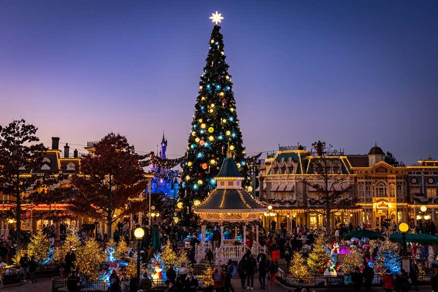 Árvore de Natal gigante iluminada à noite na praça principal da Disneyland® Paris