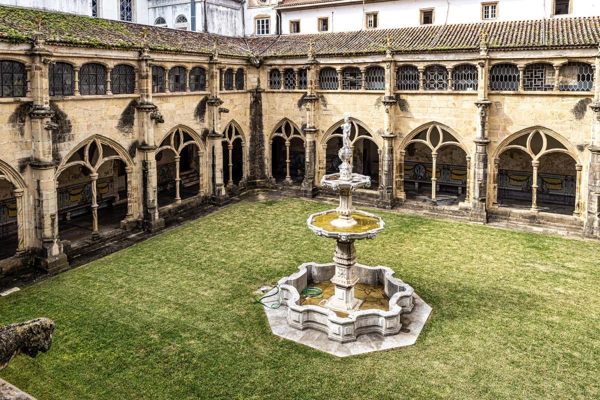 Claustro em estilo manuelino com fonte central e jardim gramado em Coimbra