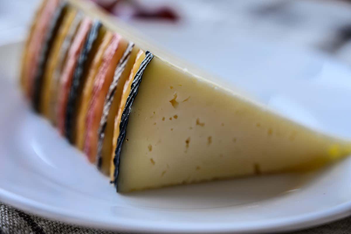 Cuña de queso manchego curado con corteza sobre plato blanco
